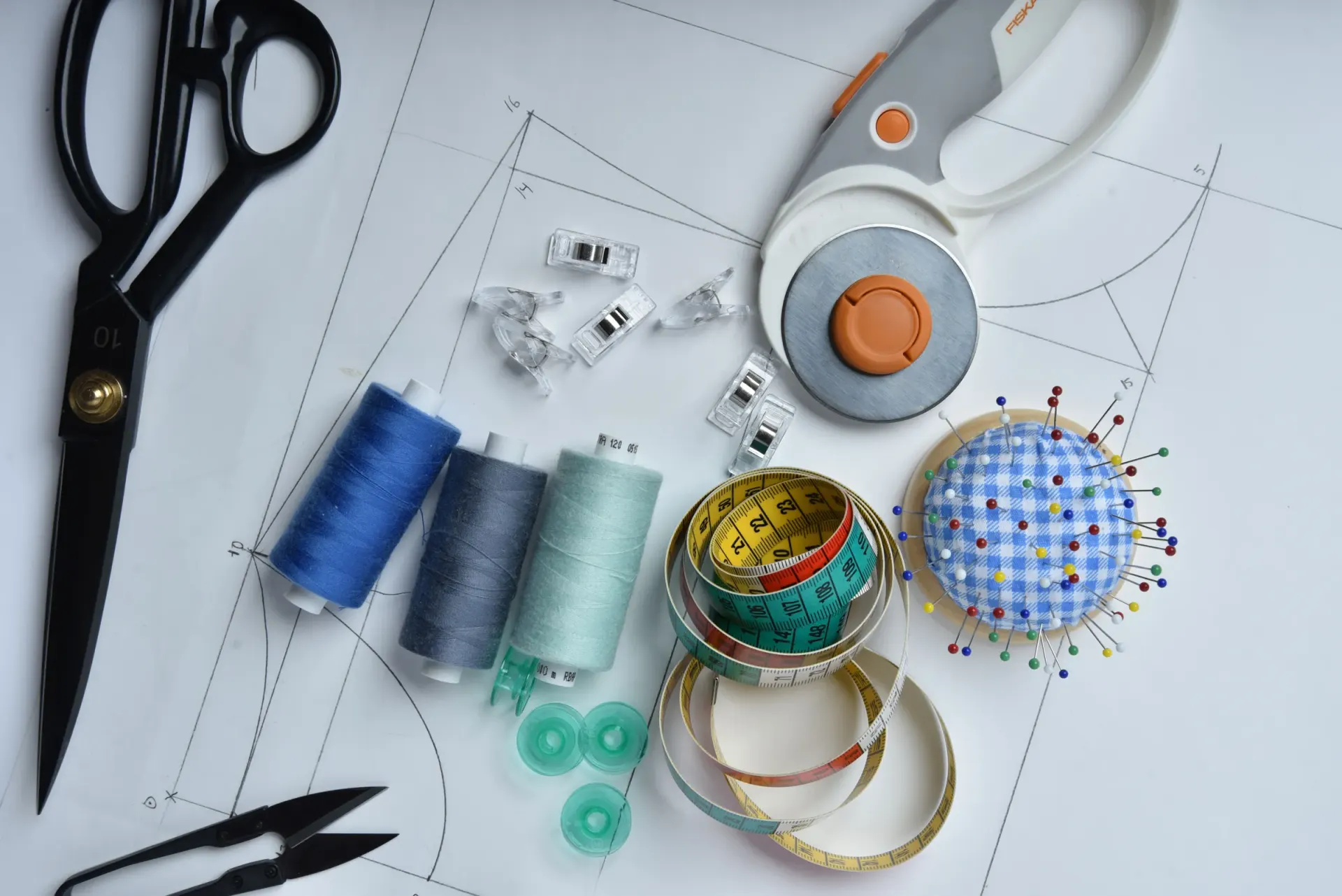 Pattern-cutting tools, threads and pins laid out on a paper pattern